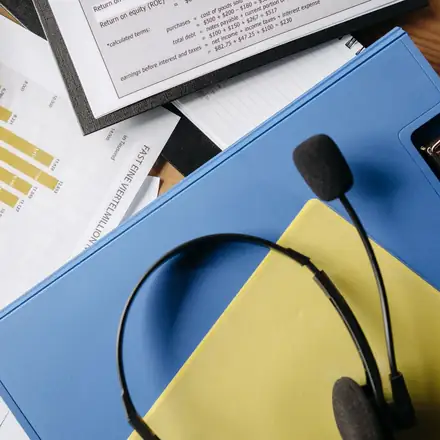 A headset resting on a folder of call notes