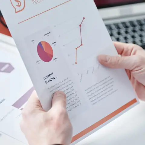Hands holding a printed report with charts
