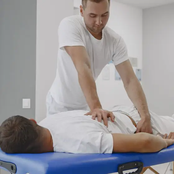 A chiropractor pressing on a patient’s lower back on a treatment table