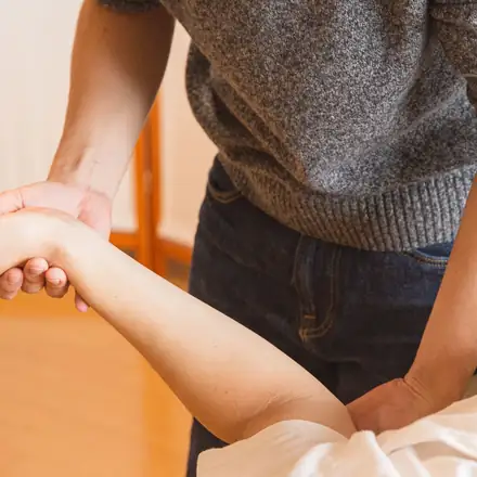 A practitioner stretching a patient’s arm at the wrist and shoulder
