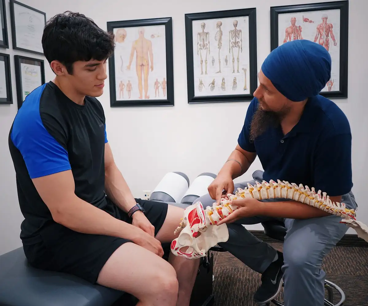 A chiropractor showing a patient a model of the spine