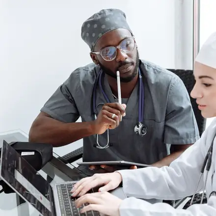 Two clinicians reviewing documentation on a laptop