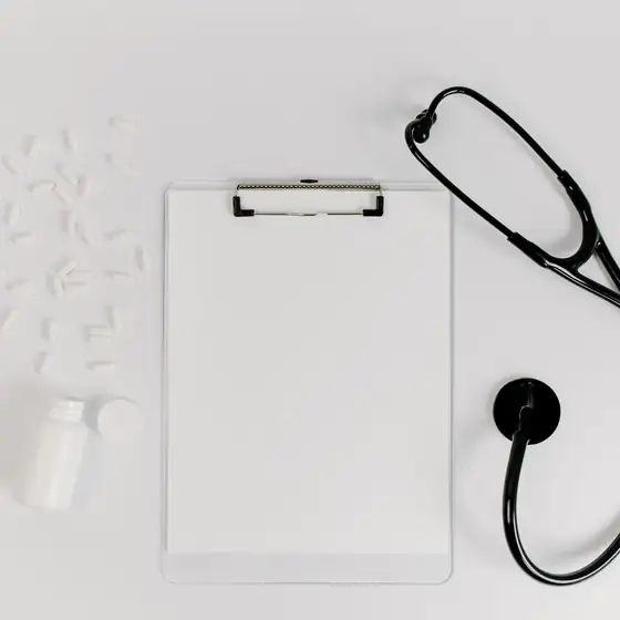 A clipboard and a stethoscope on a white desk