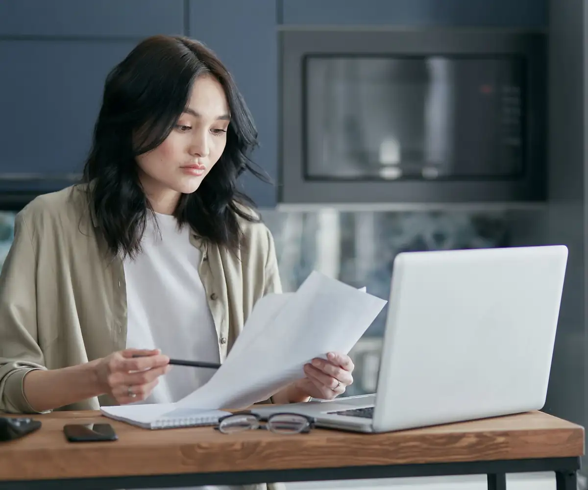 A coder reviewing documentation beside her laptop