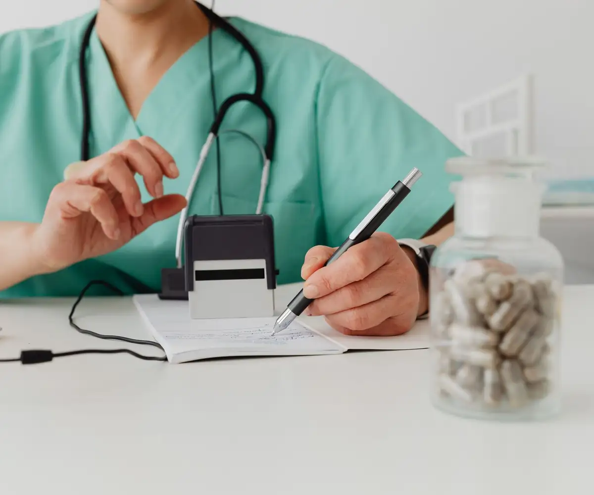 A clinician stamping and signing paperwork at a desk