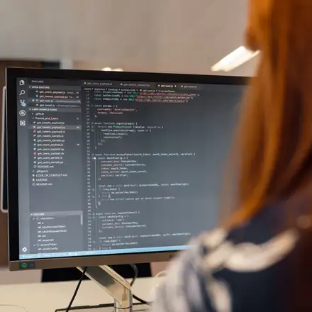 A developer writing code on a large monitor