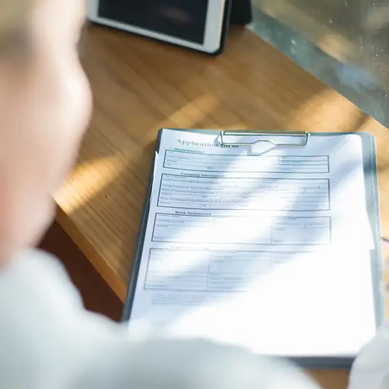 A person reviewing a form on a clipboard at a desk