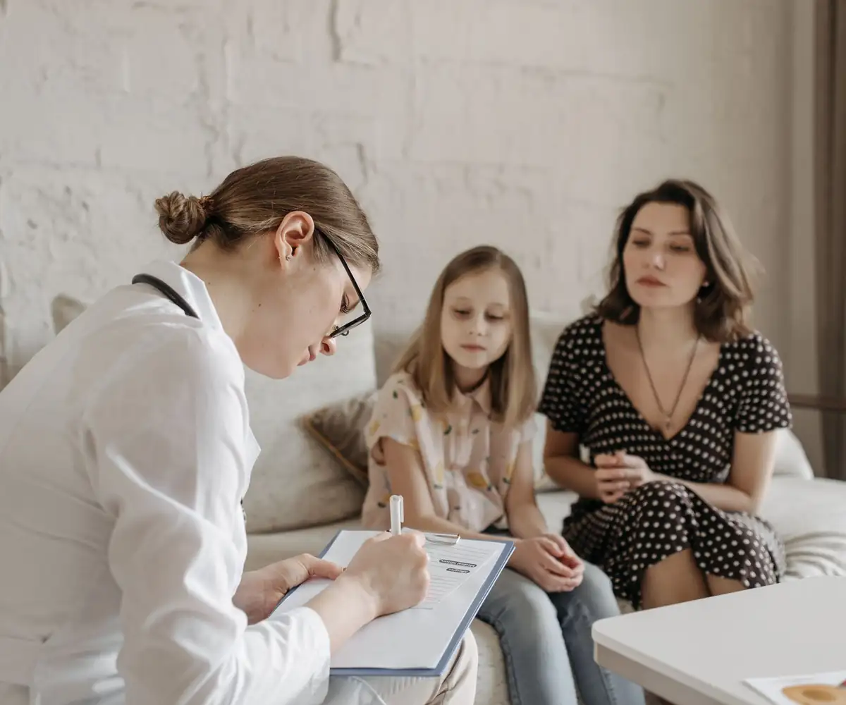A doctor talking with a mother and her daughter at home