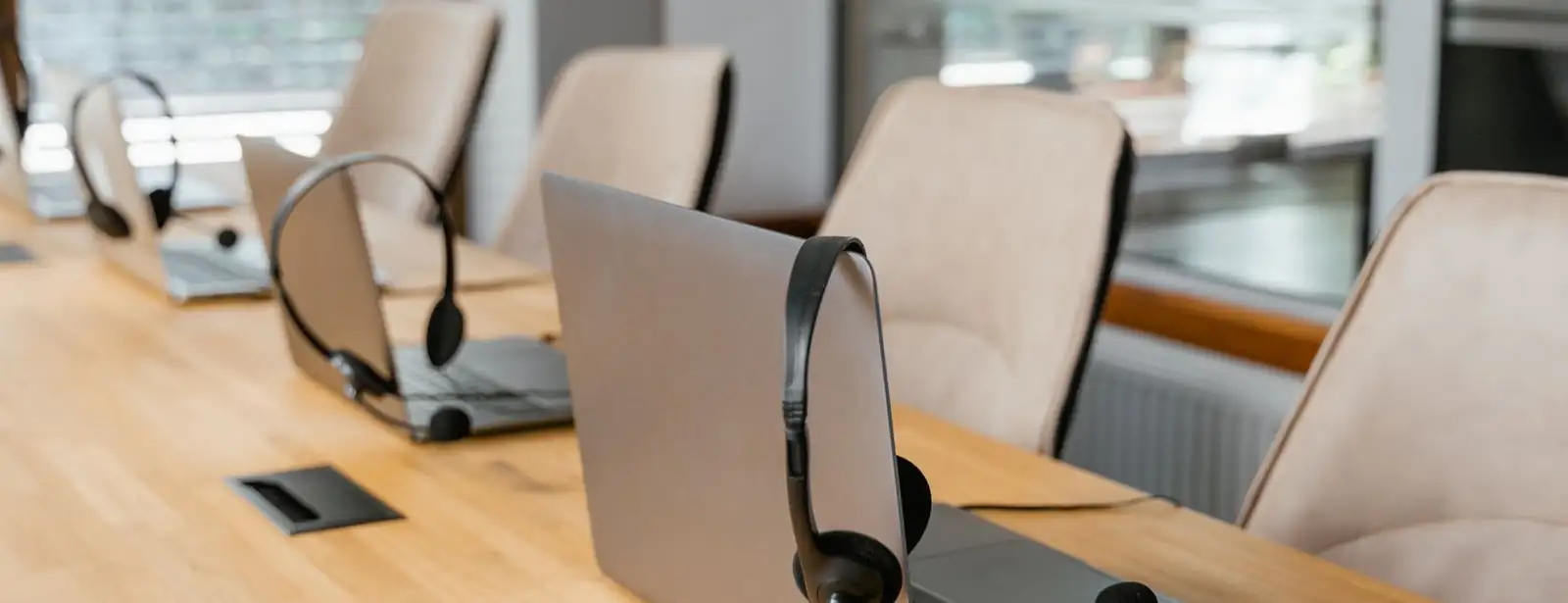 A row of laptops with headsets, set up and ready for work