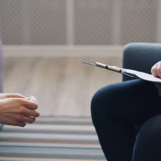 A counselor with a clipboard sitting across from a client