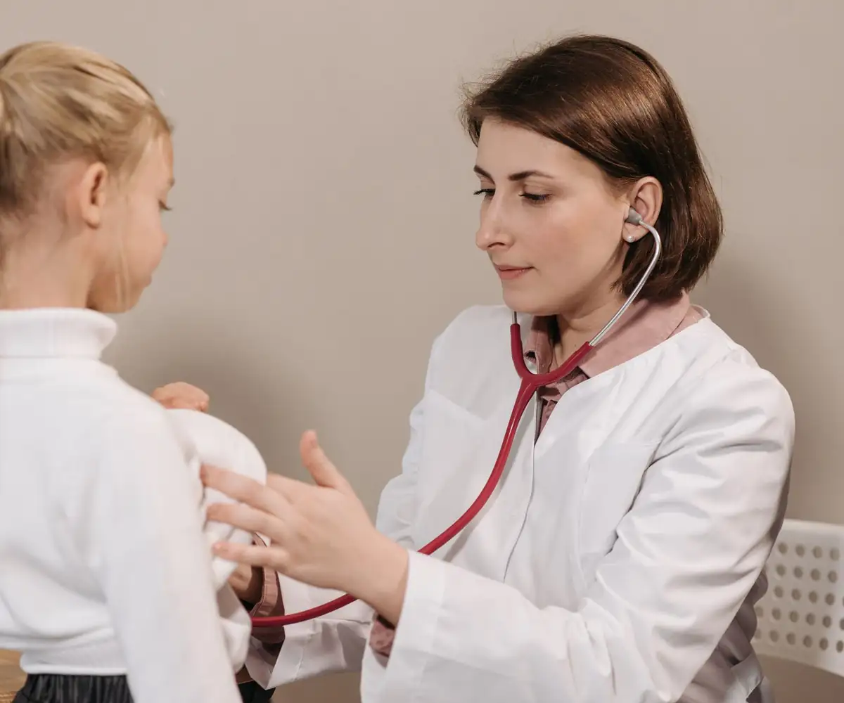 A pediatrician listening to a girl’s breathing