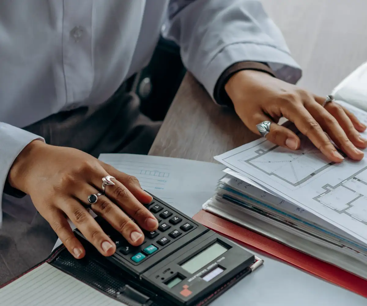 Hands working a calculator over a ledger