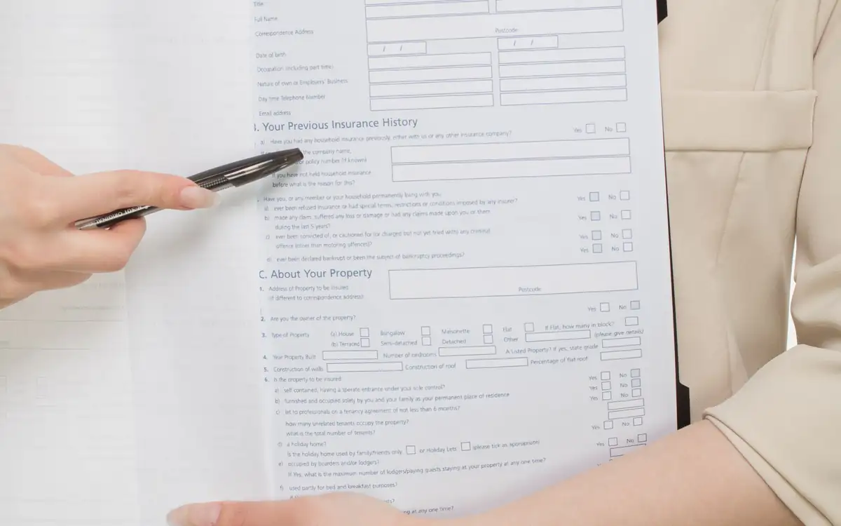 A hand holding an application form and a pen