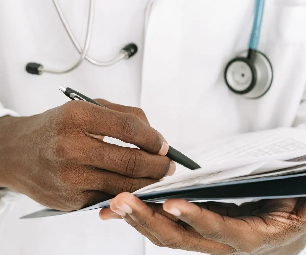 A doctor filling in a form on a clipboard