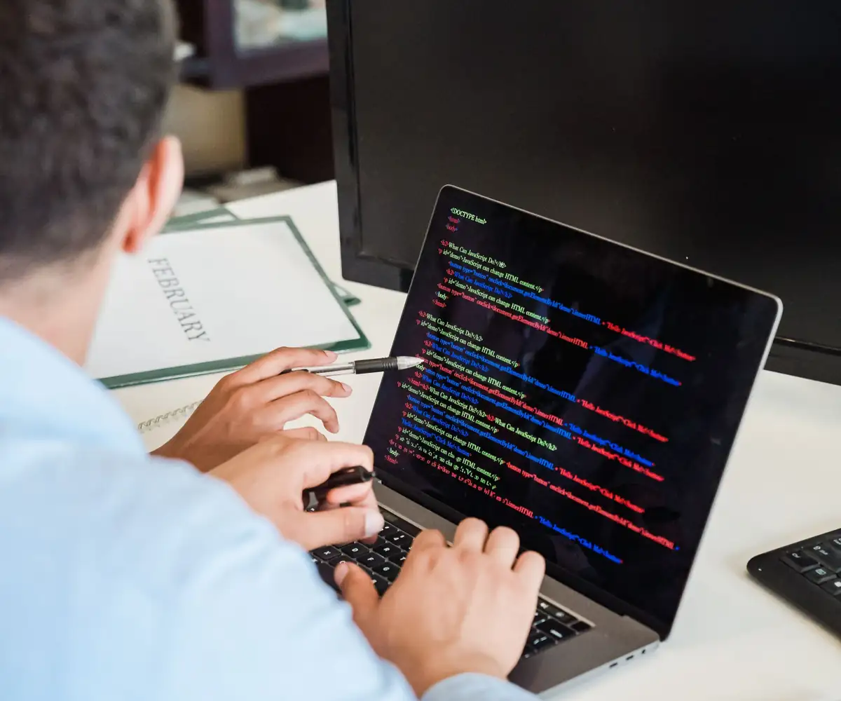 A developer writing code on a laptop