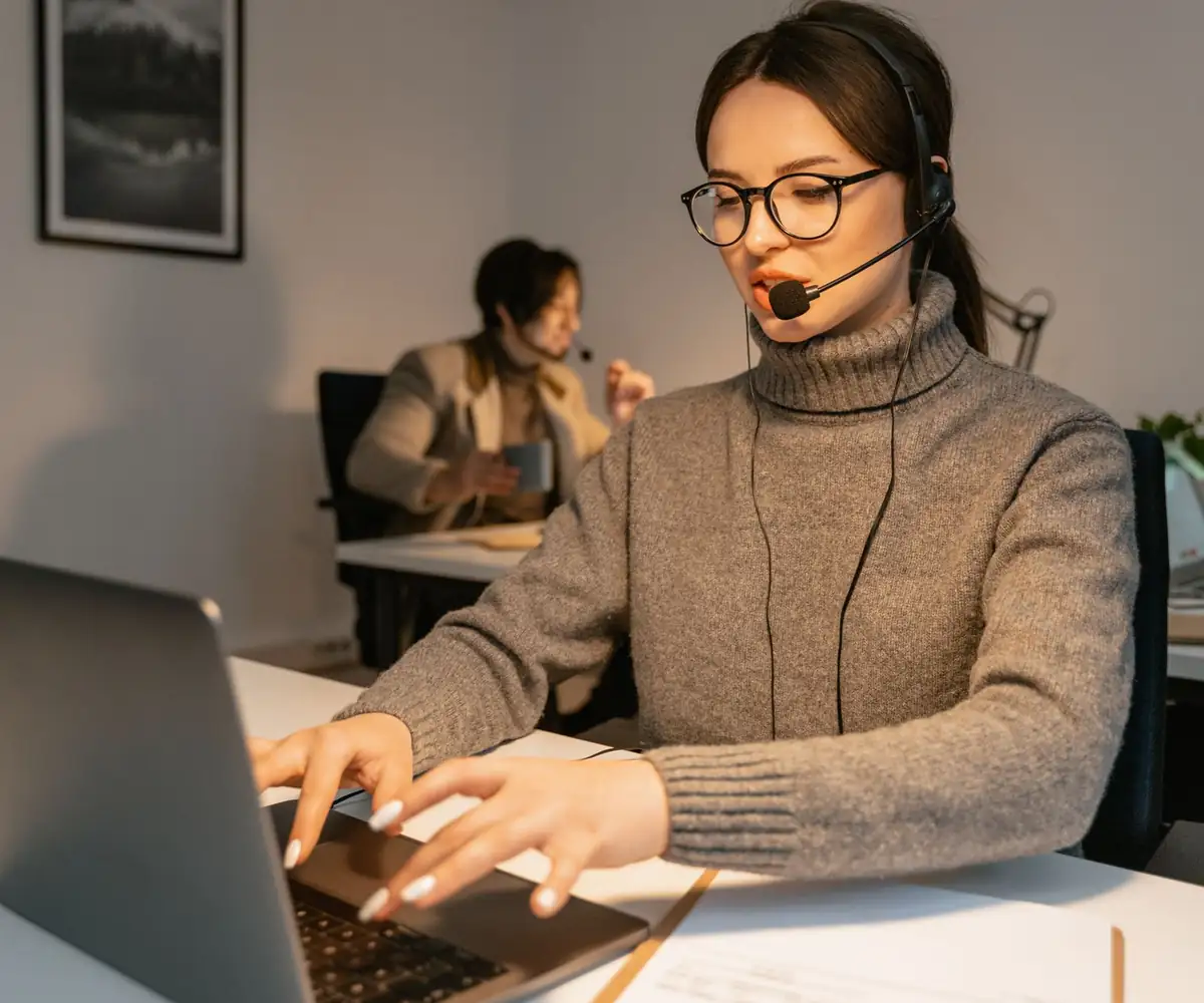 A virtual assistant with a headset typing at her laptop