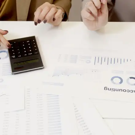 Two people checking a remittance with a calculator