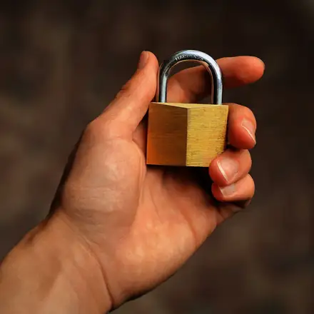 A hand holding a brass padlock