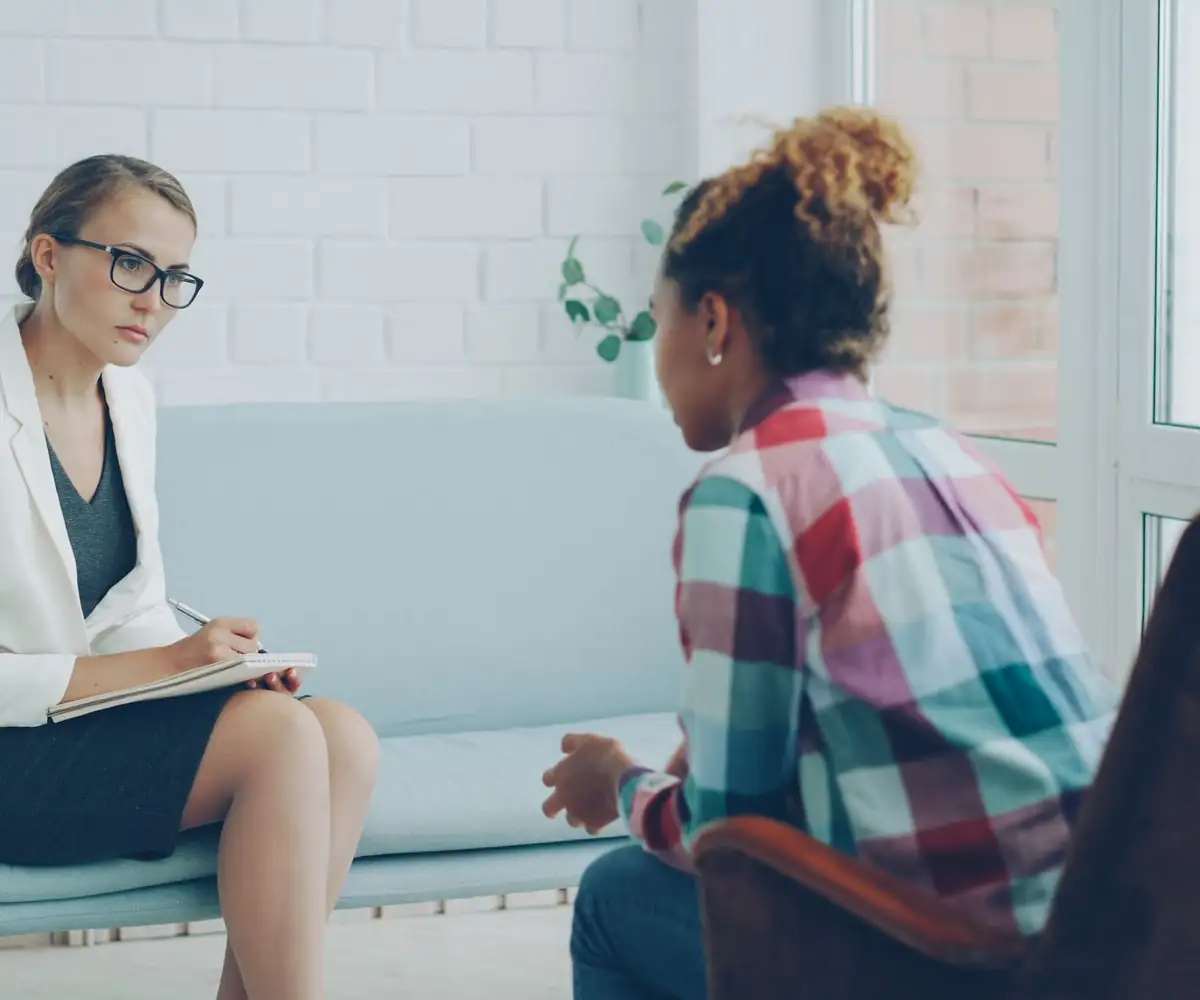 A therapist taking notes while a client talks