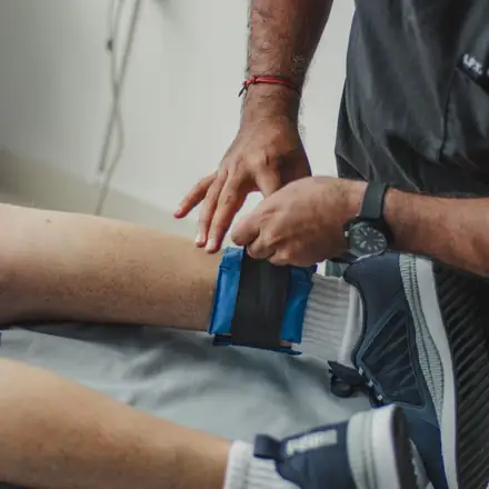 A therapist fastening a strap around a patient’s ankle