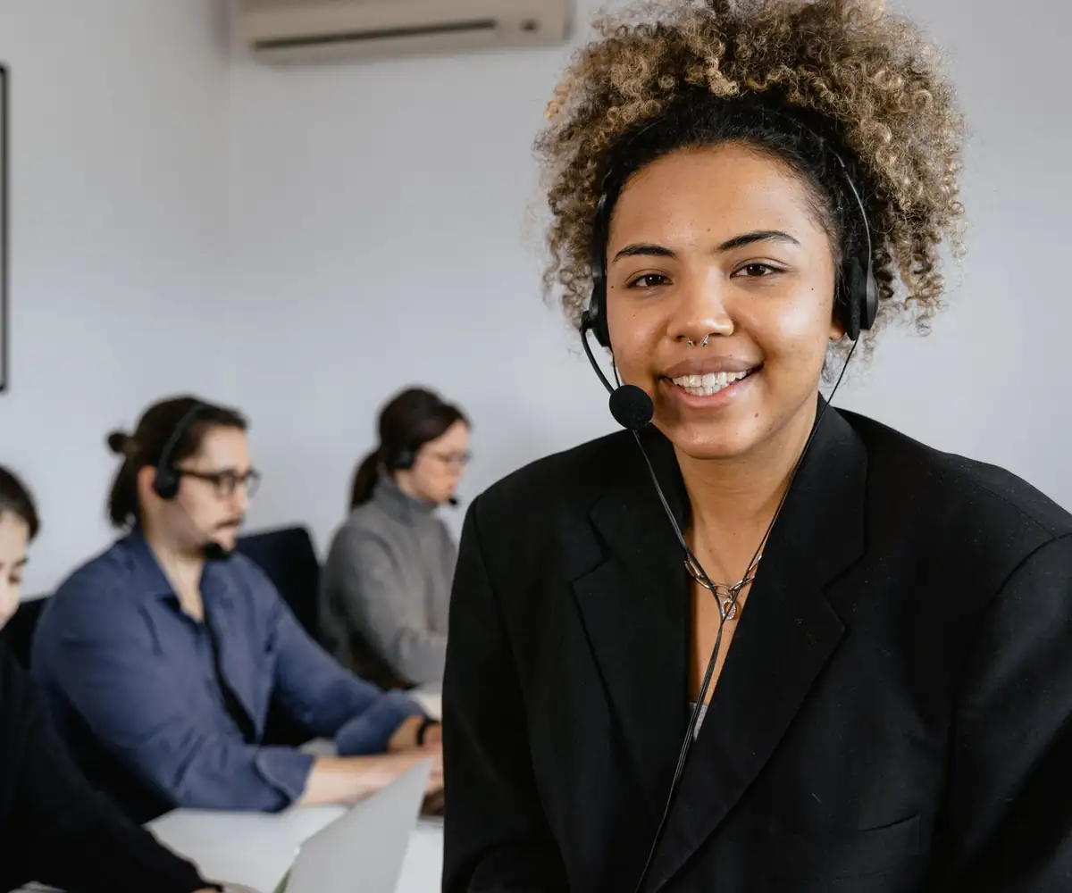 A smiling support specialist wearing a headset at her desk