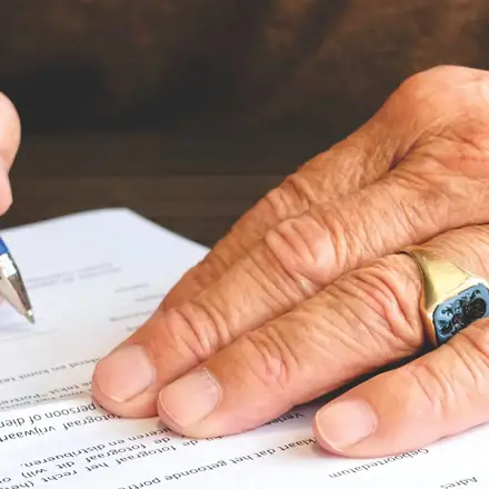 A hand signing a document