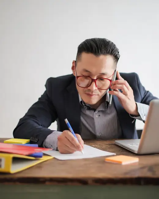 An A/R specialist on a call, taking notes