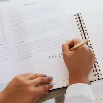 Hands signing a page in a notebook