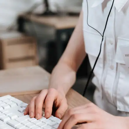 An assistant with a headset typing at her desk