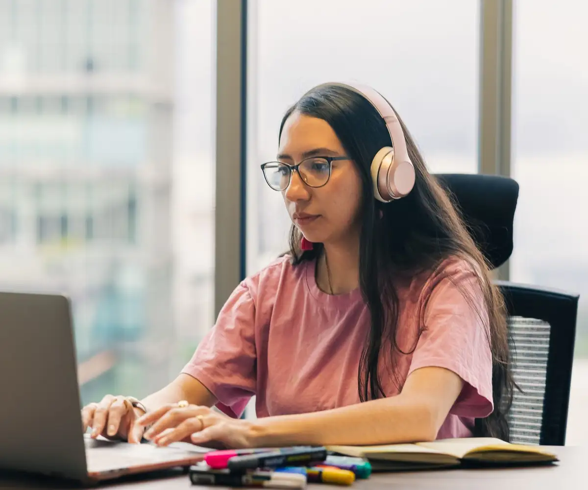A virtual assistant with headphones working at her laptop