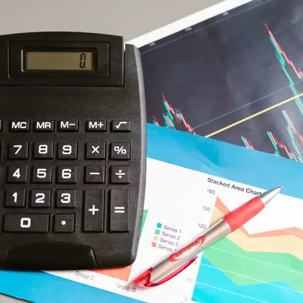 A calculator and a pen on a page of charts